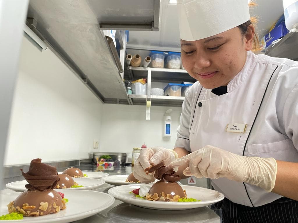 A culinary crew member plating desserts in a professional galley